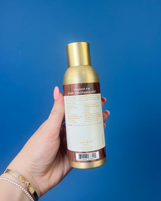 Thymes Frasier Fir Home Fragrance Mist bottle displayed on a solid blue background. 