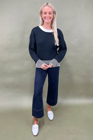 Black knit sweater with striped trim styled with dark wide leg cropped jeans and white loafers, casual fall outfit