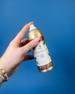 Thymes Frasier Fir Home Fragrance Mist bottle displayed on a solid blue background. 