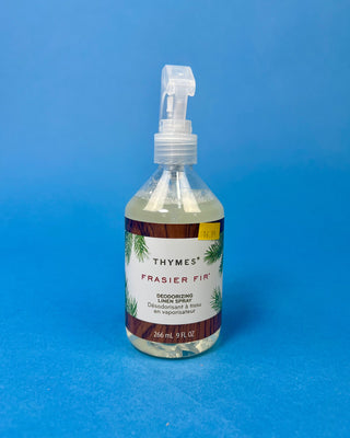 Thymes Frasier Fir 9 oz. Deodorizing Linen Spray displayed against a solid blue background.
