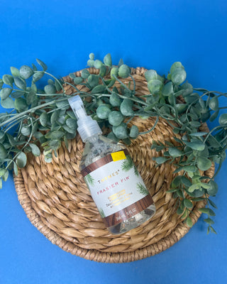 Thymes Frasier Fir 9 oz. Deodorizing Linen Spray displayed against a solid blue background.