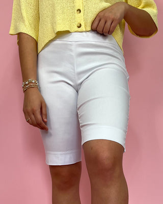 Person wearing a yellow top and white shorts against a pink background