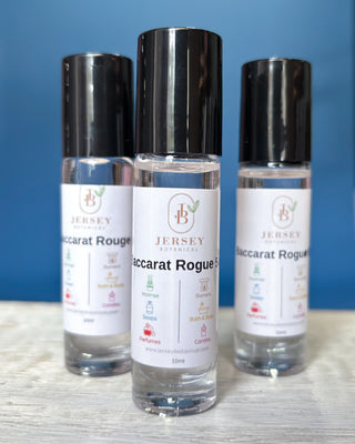 Baccarat Rouge roll-on perfume bottles displayed on a wooden surface with a blue background.