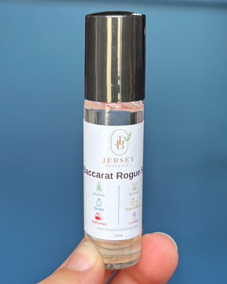 Baccarat Rouge roll-on perfume bottles displayed on a wooden surface with a blue background.