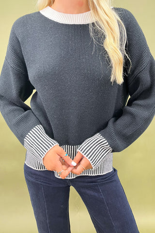 Black knit sweater with striped trim styled with dark wide leg cropped jeans and white loafers, casual fall outfit