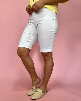 Person wearing white shorts and yellow top on a pink background
