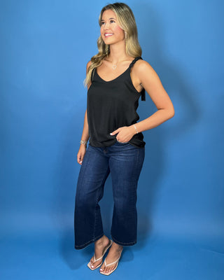 Black sleeveless satin camisole top with a V-neckline, braided shoulder straps, and relaxed silhouette.