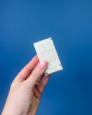 A bottle and box of Thymes Frasier Fir natural fragrance, shown on a solid blue background. 