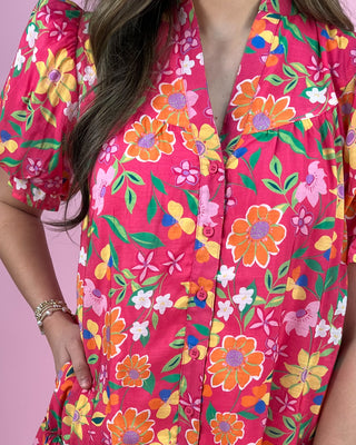 Person wearing a bright pink floral dress against a pink background