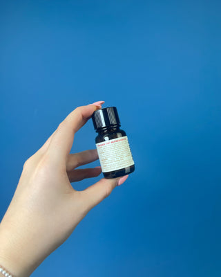Thymes Frasier Fir Refresher Oil in amber glass bottle with signature evergreen label displayed on a solid blue background.