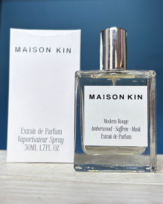 Maison Kin perfume bottle and packaging on a blue background