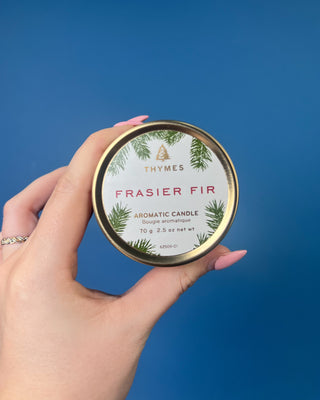 Thymes Frasier Fir Travel Tin Candle displayed on a solid blue background. 