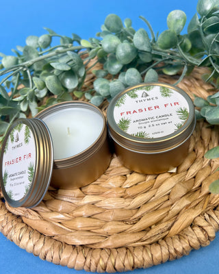 Thymes Frasier Fir Travel Tin Candle displayed on a solid blue background. 