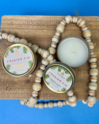 Thymes Frasier Fir Travel Tin Candle displayed on a solid blue background. 