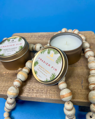 Thymes Frasier Fir Travel Tin Candle displayed on a solid blue background. 