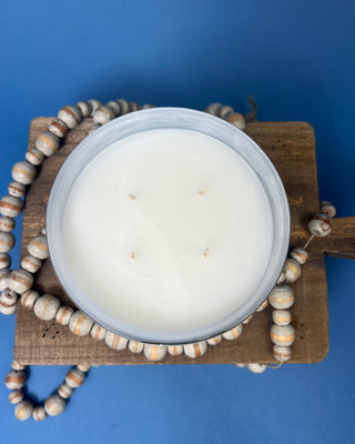 Thymes Frasier Fir Tidings 21 oz. marbled glass candle displayed on a solid blue background. 