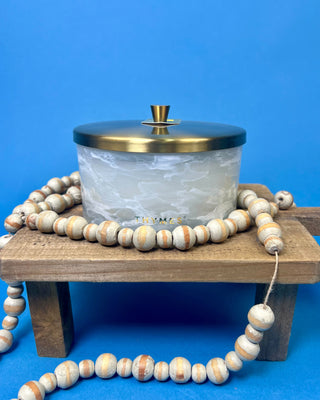 Thymes Frasier Fir Tidings 21 oz. marbled glass candle displayed on a solid blue background. 