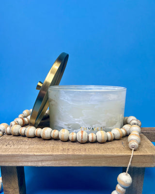 Thymes Frasier Fir Tidings 21 oz. marbled glass candle displayed on a solid blue background. 
