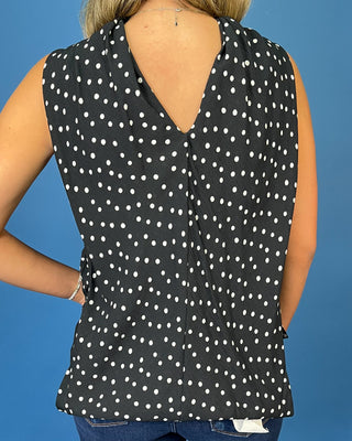 Black and white polka dot sleeveless top with a draped high neckline, gathered detail, and relaxed fit.