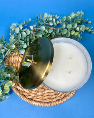 Thymes Frasier Fir Tidings 21 oz. marbled glass candle displayed on a solid blue background. 