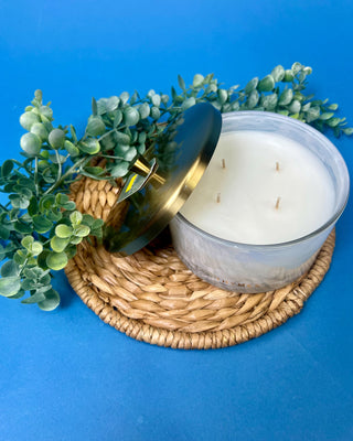 Thymes Frasier Fir Tidings 21 oz. marbled glass candle displayed on a solid blue background. 