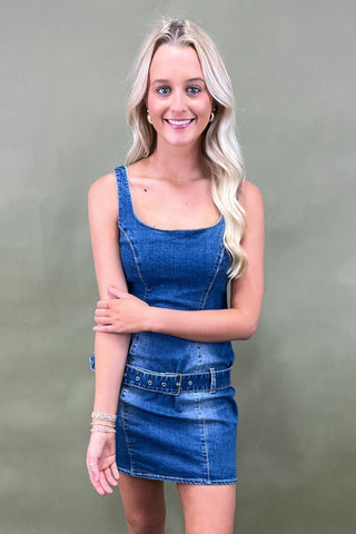 Woman wearing a blue denim dress against a plain background