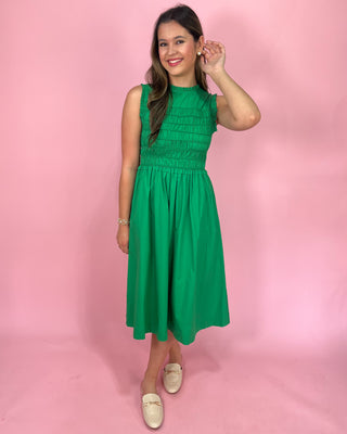 Woman wearing a green dress against a pink background