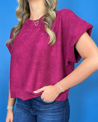 Berry magenta short sleeve top with a round neckline, relaxed fit, cuffed sleeves, and subtle textured fabric.