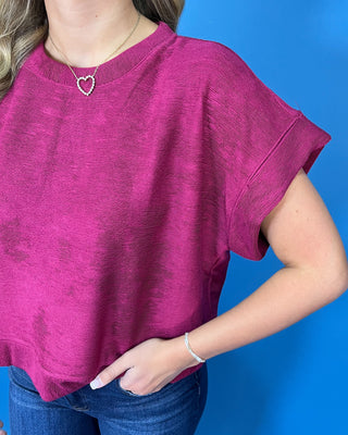 Berry magenta short sleeve top with a round neckline, relaxed fit, cuffed sleeves, and subtle textured fabric.