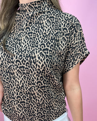 Leopard print top worn by a person on a pink background