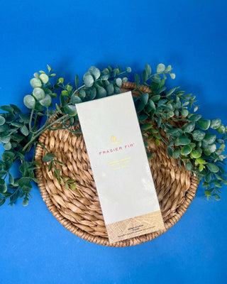 Thymes Frasier Fir Petite Gold Diffuser with reeds displayed on a solid blue background. 