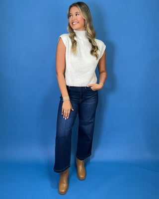 Ivory ribbed knit sleeveless sweater top with a high mock neckline, structured shoulders, and subtle chevron knit detailing