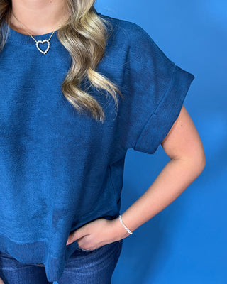 Deep teal blue short sleeve top with a round neckline, cuffed sleeves, relaxed fit, and subtle textured finish.