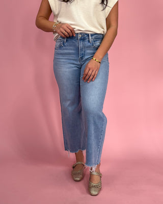 Person wearing blue jeans and a white shirt on a pink background