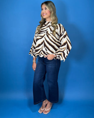 Brown, ivory, and tan zebra print mock neck sweater with bell sleeves, relaxed fit, and scalloped hem detailing.