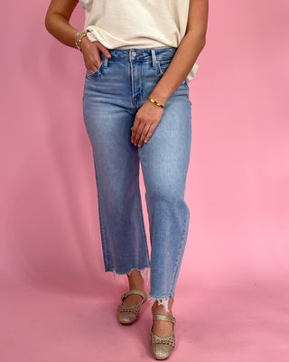 Person wearing light blue jeans on a pink background