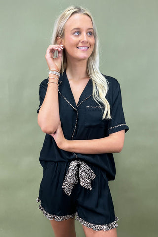 Woman wearing a black outfit with leopard print details on a green background