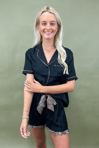 Woman wearing a black outfit with decorative elements on a green background