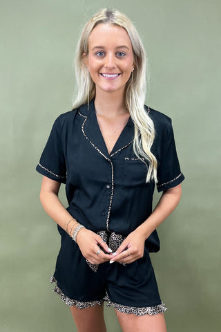 Woman wearing a black outfit with decorative trim on a green background