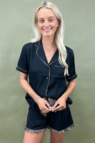 Woman wearing a black outfit with decorative trim on a green background