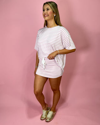 Woman wearing a white and pink striped outfit on a pink background