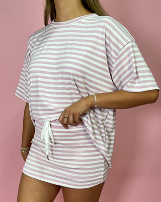 Person wearing a pink and white striped outfit against a pink background