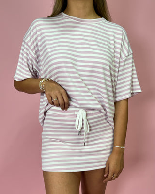 Person wearing a pink and white striped dress against a pink background