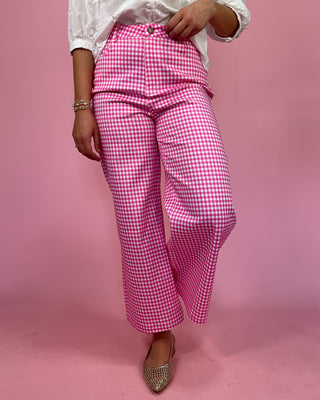 Person wearing pink checkered pants on a pink background