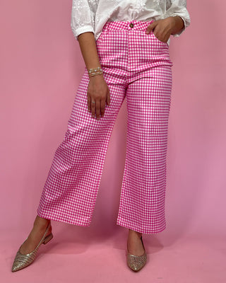 Person wearing pink gingham pants on a pink background