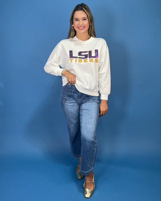 A woman modeling a white LSU Tigers sweatshirt, paired with blue jeans,