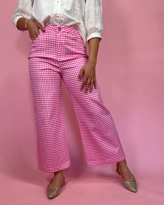 Person wearing pink checkered pants on a pink background