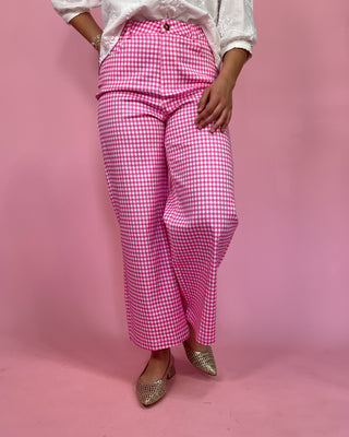 Person wearing pink checkered pants on a pink background