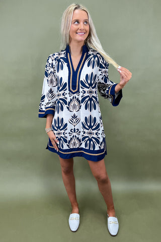 Woman wearing a patterned dress with long sleeves against a green background