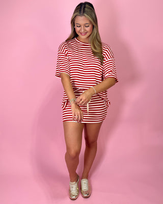 Woman wearing a red and white striped outfit on a pink background